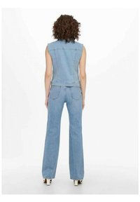 Ținută din denim compusă dintr-o vestă fără mâneci, ajustată, de culoare albastru deschis, și blugi evazați de culoare albastru deschis, evidențiind o textură netedă și detalii de cusătură minime.