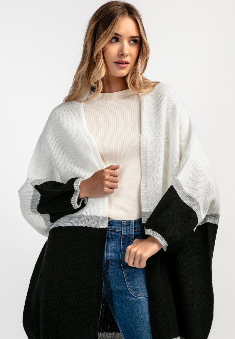 Czarny i biały otwarty kardigan z oversize'owymi rękawami, z teksturowanym wzorem dzianiny i jednolitą czarną sekcją na dole.