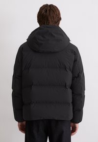Schwarze Steppjacke mit Kapuze, die ein gequiltetes Design und elastische Bündchen aufweist. Glatte, matte Oberfläche mit lockerer Passform.