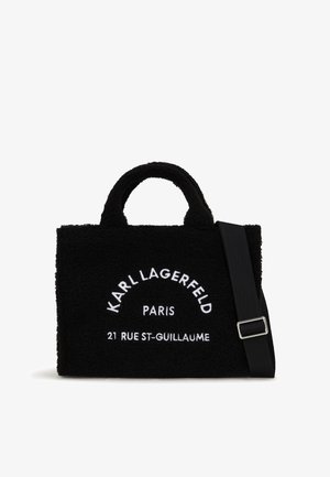 Bolso tote negro texturizado con dos asas superiores y una correa para el hombro desmontable. Presenta texto bordado en blanco "KARL LAGERFELD PARIS" y dirección.