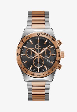 Montre chronographe avec un cadran noir, accents en or rose, boîtier en acier inoxydable, lunette tachymétrique et bracelet métallique à maillons.