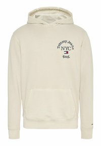 Felpa color crema realizzata in tessuto morbido, con tasca frontale e logo ricamato "Tommy Jeans NYC" sul petto.
