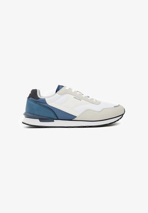 Zapatillas deportivas con un upper de malla blanca, acentos de ante gris y superposiciones sintéticas en azul marino. Presentan una entresuela blanca y una suela de goma negra.