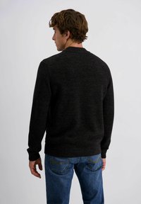 Donkergrijze trui met een ronde hals, lange mouwen en geribde manchetten, gecombineerd met een blauwe spijkerbroek. De textuur lijkt glad en gebreid.