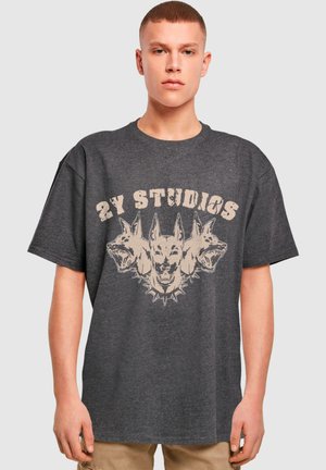 Grå oversized t-skjorte laget av bomull, med et sentralt grafikk av tre hundehoder med "2Y STUDIOS"-tekst over i beige.