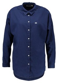 Donkerblauwe button-up shirt van katoen, met een puntige kraag, lange mouwen en een lichte curve aan de zoom. Voorkant met borstzak en logo-label.