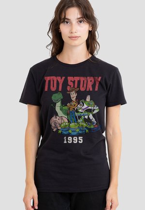 Young woman wearing black "Toy Story 1995" T-shirt with characters Woody, Buzz Lightyear, Rex, Hamm, and three green aliens on front.