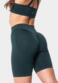 Donkergroene sportshorts van rekbare stof, met een hoge tailleband en gestructureerde patronen op de zijkanten voor verbeterde grip.