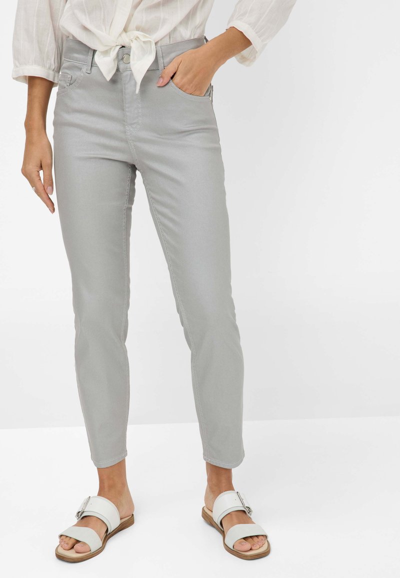 Hellgraue Slim-Fit-Jeans aus Baumwollmischung mit Fronttaschen, Reißverschluss und gestickten Details, kombiniert mit weißen Sandalen.