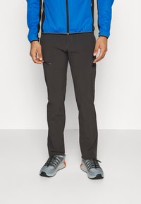 Herrarnas utomhusbyxor i mörkgrått med en slim fit, utrustade med en dragkedjeförsedd ficka och förstärkt sömnad. Matchas med gråa sportskor.