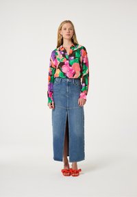 Kleurvol floral overhemd met knopen, denim maxi rok met een voorklep en zijbuttons, en oranje strik sandaaltjes. Glad textuur overal.