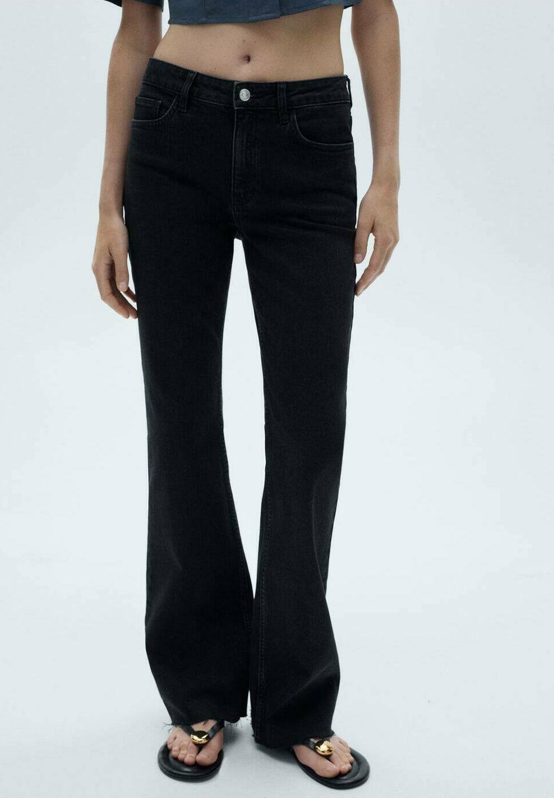 Mustat leveälahkeiset farkut, joissa on viisi taskua, keski-korkea vyötärö ja hienovarainen tekstuuri. Yhdistetty mustiin sandaaleihin.