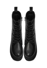 Botas negras de cuero hasta el tobillo con un acabado suave, que cuentan con cordones, cremalleras laterales y tiradores para facilitar su uso. Suelas de goma planas.