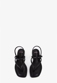 Zwarte platte sandalen met een slank ontwerp, voorzien van kruisende banden en een vierkante neus. Gemaakt van soepel leer met een minimalistische esthetiek.
