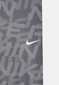Nike-produkt med et stripet mønster i svart og hvitt. Har en hvit Nike-logo og en teksturert overflate. Designet inkluderer geometriske former.