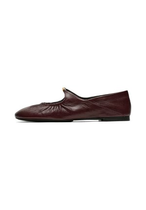 Chaussure plate en cuir brun foncé avec un détail élastiqué froncé près de l'ouverture et un petit accent métallique sur le bord avant supérieur.