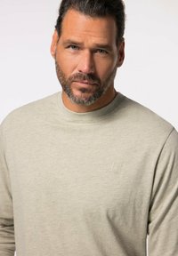 Sudadera de cuello redondo de manga larga en gris claro con un acabado texturizado y un sutil logo grabado en el pecho. Tejido suave con un corte relajado.