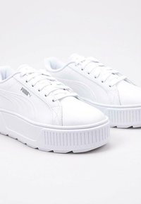 Białe sneakersy na platformie z gładką syntetyczną cholewką, okrągłym noskiem, tonowymi sznurowadłami oraz teksturowaną gumową podeszwą z pionowymi rowkami.