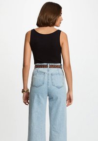 Black ribbed tank top with a round neckline, paired with high-waisted light blue denim jeans featuring a leopard print belt.