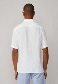 Short-sleeve, white linen shirt with a classic collar and textured fabric, featuring a straight hem and rolled cuffs.