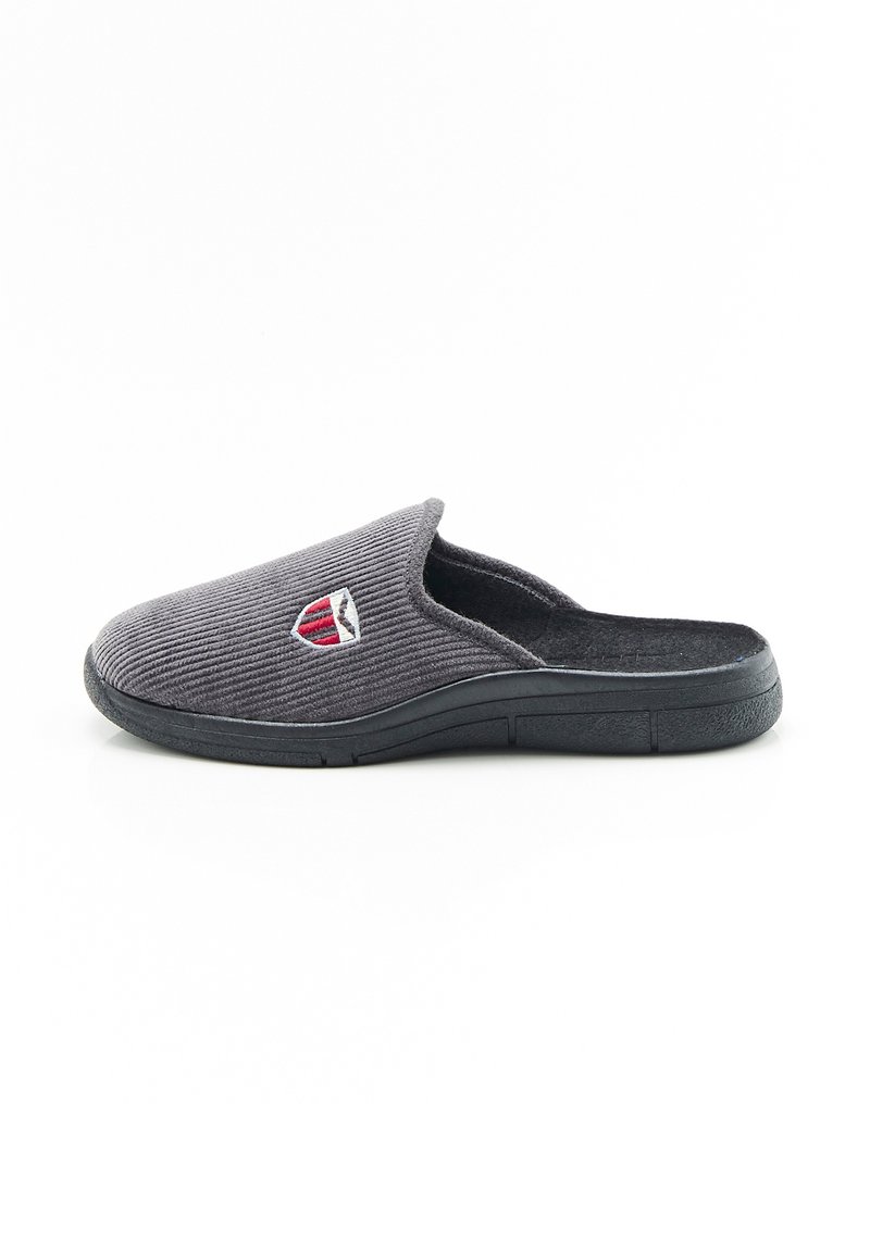 Pantofole slip-on in corduroy grigio con suola nera e emblema a scudo rosso e bianco sulla parte superiore, isolate su sfondo bianco.