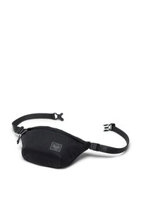 Sac banane en nylon noir avec une forme courbée, une sangle réglable et une poche zippée à l'avant. Présente une petite étiquette de marque à l'avant.