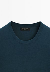 Niebieski bawełniany sweter z okrągłym dekoltem o teksturowanym wykończeniu. Zawiera czarną metkę z białym nadrukiem "Massimo Dutti". Gładki design, bez wzorów.