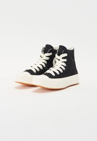 Zapatillas de caña alta con un upper texturizado negro, cordones color crema y una puntera de goma blanca. Suela de goma y detalle del logo incluidos.