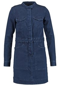 Tummafarkkumekko, jossa kauluksellinen pääntie, pitkät hihat, kaksi rintataskua, vyötäröllä vyö ja sivutaskut.