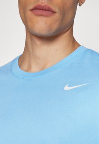 Lys blå bomull T-skjorte med rund hals, med en liten hvit Nike-logo på brystet, glatt tekstur og korte ermer.