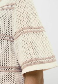 Knit felső világos krém színben, kontrasztos barna csíkokkal, laza szabással és texturált szőtt mintával. Rövid ujjak.