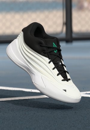 White and black athletic sneaker with textured sole and laces, floating above blue outdoor sports court surface.