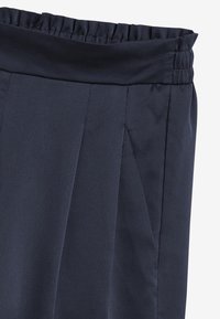 Navy pleated pants featuring an elastic waistband and smooth texture, designed with side pockets for functionality.