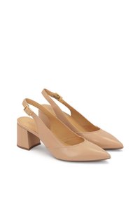 Beige nahkakengät, joissa on osoitinuttu, matala lohkokorko ja säädettävä hihna, jossa on kultaiset yksityiskohdat.