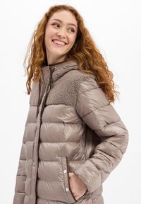 Puffige, taupe-farbene Jacke mit einem strukturierten, braunen Fleece-Oberteil und Kapuze. Verfügt über Druckknöpfe und Seitentaschen für praktischen Nutzen.