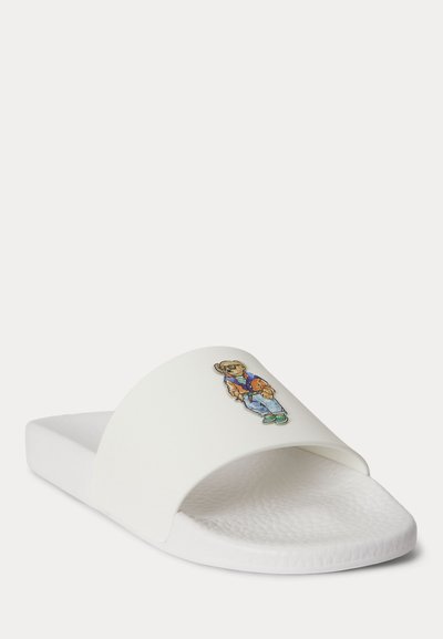 Λευκό σανδάλι με υφή στη σόλα και τύπωμα αρκούδας που φοράει καθημερινά ρούχα στο λουράκι.