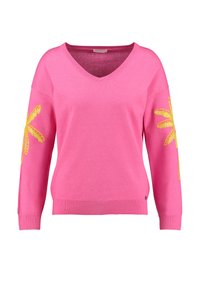 Maglione rosa acceso con scollo a V, maniche lunghe e decorazioni floreali gialle su entrambe le braccia. Tessuto a maglia morbido con orlo a coste.