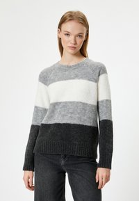 Grauer und weiß gestreifter Pullover mit geripptem Saum. Hergestellt aus weichem Material, mit Rundhalsausschnitt und langen, weit geschnittenen Ärmeln.