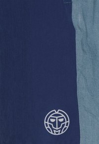 Marineblauer und hellblauer Stoff mit glatter Textur, auf dem marineblauen Bereich befindet sich ein weißes rundes Logo. Vertikales Farbblock-Design.