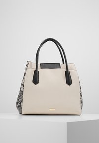 Beige och svart handväska med en strukturerad form, som har slät konstläder och ett texturerat ormskinnsmönster på ena sidan.