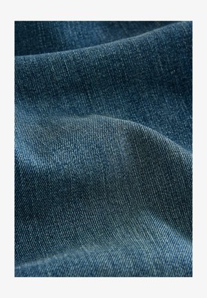 Tissu en denim bleu foncé avec une texture lisse et un motif de tissage en sergé visible, mettant en valeur un drapé doux et des variations de couleur subtiles.