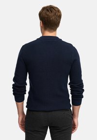 Dunkelblauer Strickpullover mit ribbeliger Textur, ausgestattet mit langen Ärmeln und einem umgeschlagenen Kragen, als Pullover im taillierten Design gestaltet.