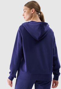 Felpa con cappuccio blu navy con vestibilità rilassata, polsini e orlo a costine. Realizzata in tessuto morbido con una texture liscia.