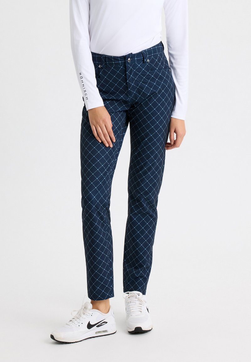 Pantalones de patrón navy con un diseño de diamantes y acentos en azul claro, fabricados con un material suave. Combinados con zapatillas blancas.