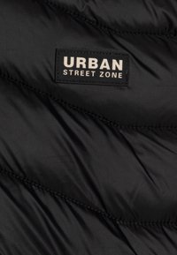 Black puffer jacket section with quilted design, featuring a prominent rectangular label that reads "URBAN STREET ZONE" in white text.