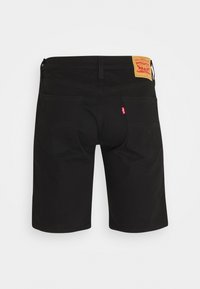 Pantalones cortos de mezclilla negros con un diseño clásico de cinco bolsillos, que cuentan con una etiqueta de cuero marrón y costuras curvadas distintivas en los bolsillos traseros.