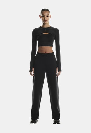 Black cropped long-sleeve top with keyhole detail, paired with loose-fitting black sweatpants. Soft, smooth fabric with minimal accents.