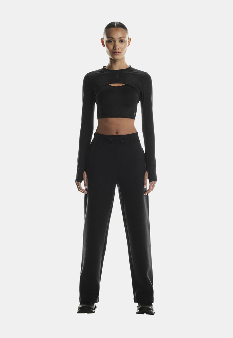 Black cropped long-sleeve top with keyhole detail, paired with loose-fitting black sweatpants. Soft, smooth fabric with minimal accents.