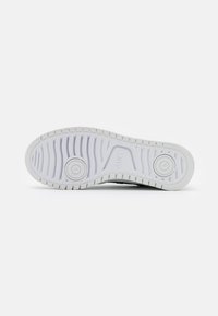 Fehér sneaker talp texturált gumival a tapadásért, két kör alakú résszel és vonalakkal a rugalmasságért. Tiszta dizájn, minimális részletezéssel.