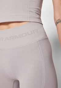 Világosszürke sport crop top és magas derekú leggings, texturált bordázással és diszkrét logó részlettel a deréknál. Sima anyagfinish.